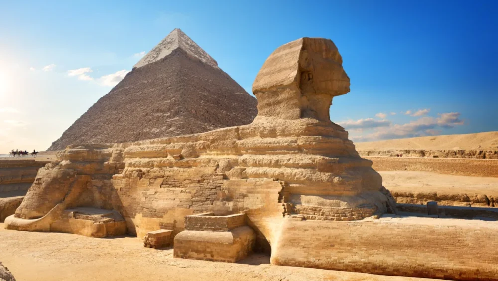 Great Sphinx and Pyramid under sunny sky.