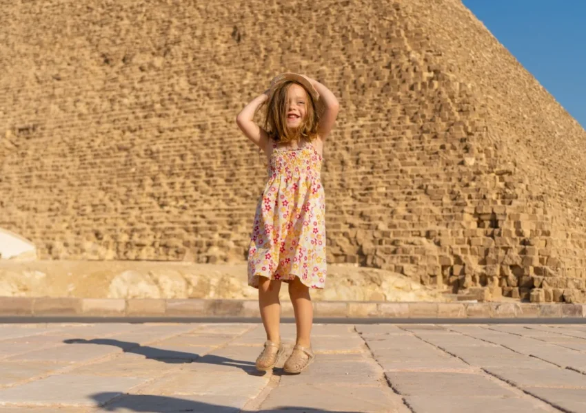 Girl in floral dress near pyramid.