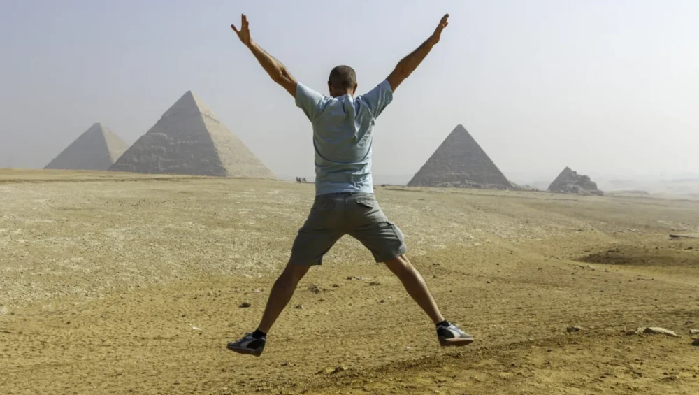 Person celebrating in front of Egyptian Pyramids.