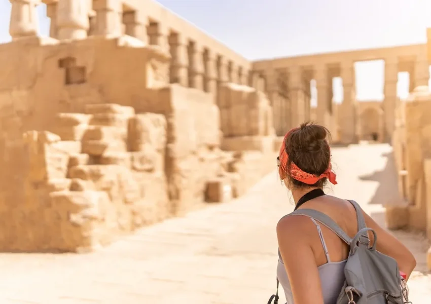 Woman exploring ancient ruins on sunny day.