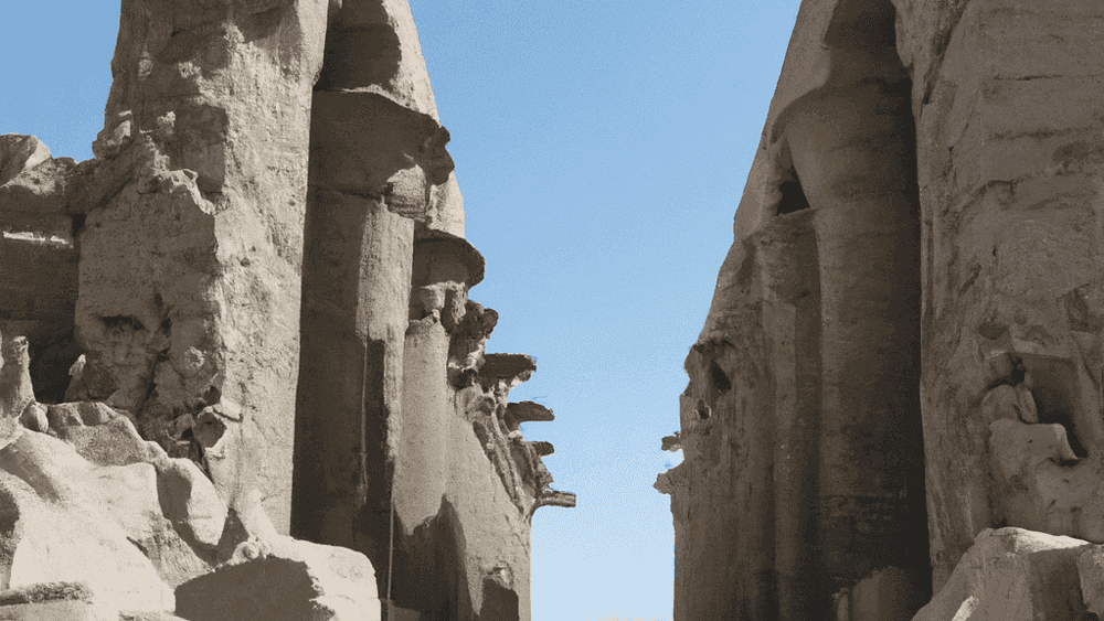 Ancient Egyptian temple ruins, stone columns, clear sky.